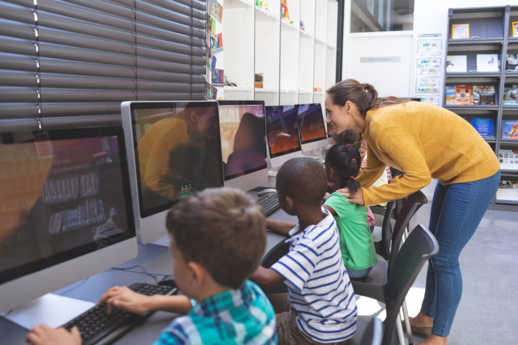 Teacher helping students with computers